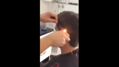 Illustration : Ce coiffeur coupe les cheveux de son client à l'aide d'un peigne et d'un... briquet